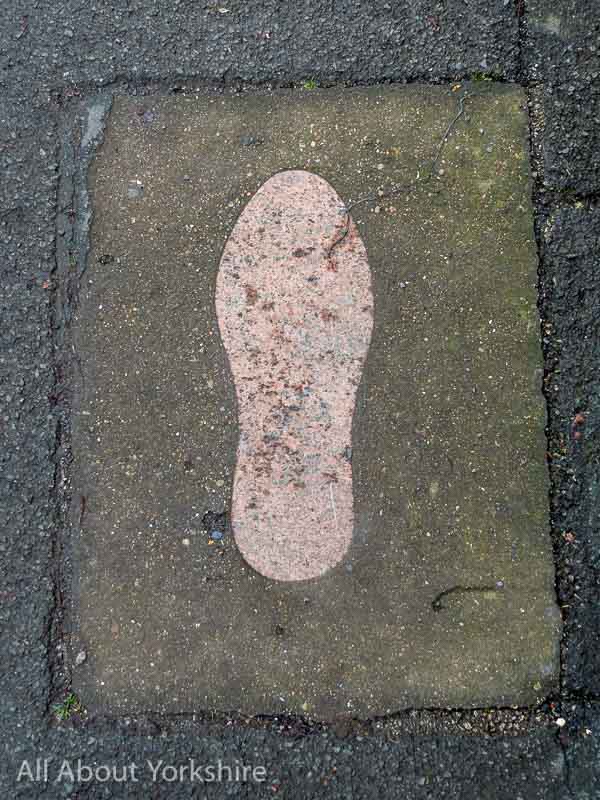 Concrete footprint set into pavement on the Giant Bradley Heritage trail