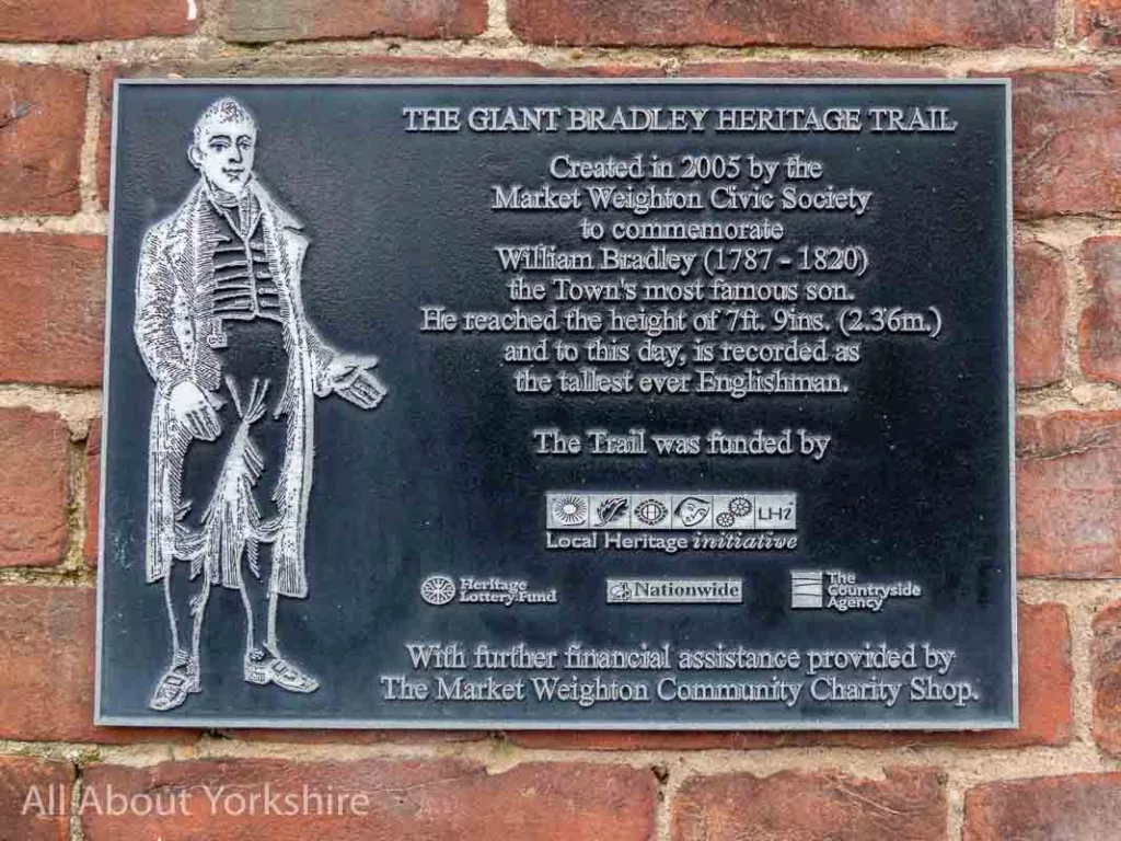Plaque that reads: The Giant Bradley Heritage Trail Created in 2005 by the Market Weighton Civic Society to commerate William Bradley (1887-1820) the town's most famous son. He reached the height of 7ft. 9ins. (2.36m.) and to this day, is recorded as the tallest ever Englishman.
